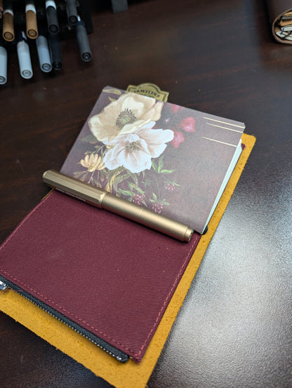 Floral notebook and pen holder on a wooden surface